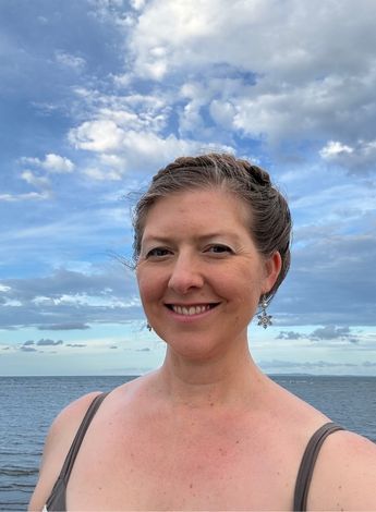 The photo is of physiotherapist Karri Field standing in front of a beach